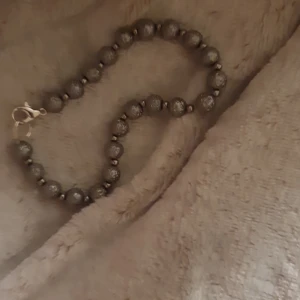 Glittrigt silverfärgat pärlarmband - Snyggt armband med glittriga silverfärgade kulor och små mellandelar mellan varje pärla. Lås i metall som är lätt att öppna och stänga. Perfekt för dig som gillar att sticka ut med lite extra bling på handleden.