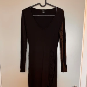 Svart maxi-klänning med slits - Svart maxi-klänning med långa armar och V-ringning. Klänningen har en elegant slits på sidan. Perfekt för både en tjejkväll och fest! Använd endast en gång.