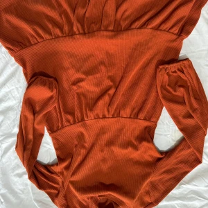 Orange ribbad klänning - Snygg orange klänning med ribbad struktur och långa ärmar. Perfekt för höst och vinter med sin varma färg och stilrena design.