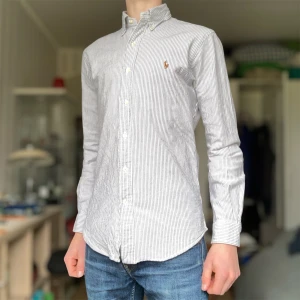 Randig skjorta från Ralph Lauren - Blårandig Ralph Lauren skjorta i bra skick. Skjortan är i storlek S och slim fit och passar typ 175 cm Enda defekten är 2 svaga deofläckar under armhålorna som syns på de sista bilderna. Dock inte synligt när man har skjortan på sig. Hör av er om frågor!  