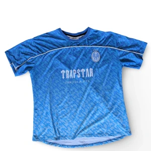Blue Trapstar Football Jersey - Trapstar Monogram Jersey – Blå Gradient Storlek: L  Skick: Som ny, använd ett par gånger  Blå Trapstar-tröja med gradientfärg och monogram print över hela. Lätt material och avslappnad passform.  Hör av dig om du vill ha fler bilder eller har några frågor.  