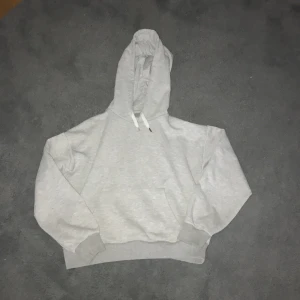 Grå hoodie från Gina Tricot - Säljer en stilren grå hoodie från Gina Tricot . Den har en klassisk design med känguruficka och justerbar huva med snören. Perfekt för en avslappnad look. Säljer pga den blivit för liten, saknar en silver detalj på ett av snörerna. Köptes för ca 200kr