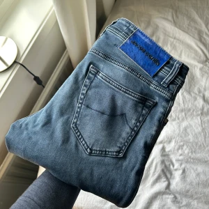 Blå jeans från Jacob Cohen - Snygga blå jeans från Jacob Cohen med klassisk femficksdesign, små slitningar och en diskret logga på bakfickan. Perfekta för en stilren look. De har en dragkedja och knapp framtill.