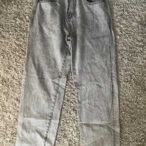 Grå jeans - Snygga grå jeansbyxor med en klassisk femficksdesign. De har en knapp och dragkedja framtill. Perfekta för en avslappnad stil.