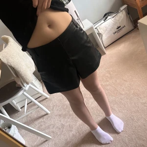 Svarta skinnshorts - Snygga svarta shorts i skinn med en stilren design. Perfekta för en trendig look. De har en normal passform och är högmidjade, vilket ger en smickrande siluett. Säljer då dem är lite stora 