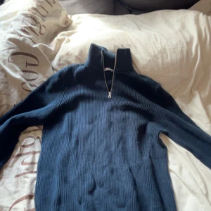 Mörkblå ribbad tröja från Zara - Säljer en stilren mörkblå ribbad tröja från Zara med dragkedja i halsen. Perfekt för kyligare dagar med sin långa ärmar och bekväma passform. Ett måste i garderoben för en avslappnad look.