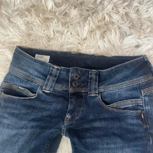 Mörkblå jeans från Pepe Jeans - (Lånade bilder, hör av er för egna, den ända skillnaden är att mina har ljusa knappar och mörk ”våg” på bakfickan). 💓Skitsnygga mörkblå jeans från Pepe Jeans med en lite bootcut passform. Måste tyvärr sälja de de inte passar mig😭 De har en klassisk femficksdesign och dubbla knappar i midjan. Perfekta för en avslappnad stil. De är i storlek 28/34💗💗