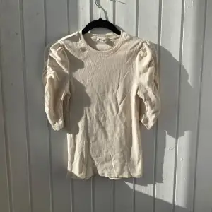 Säljer en stilren beige ribbad topp från Monki med puffiga trekvartsärmar.Toppen har en rund halsringning och är tillverkad i ett mjukt material. Inga tydliga defekter. Hör av er vid frågor!💕