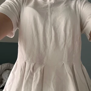 Vit blus från By Malene Birger - Säljer en stilren vit T-shirt från By Malene Birger. Tröjan har korta ärmar och en lös passform med fina veckdetaljer framtill. Perfekt för en chic och avslappnad look. Ny pris 1050