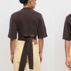 Brun kortärmad topp med knyt - Snygg brun topp med korta ärmar och knytning i ryggen. Perfekt för en stilren look.