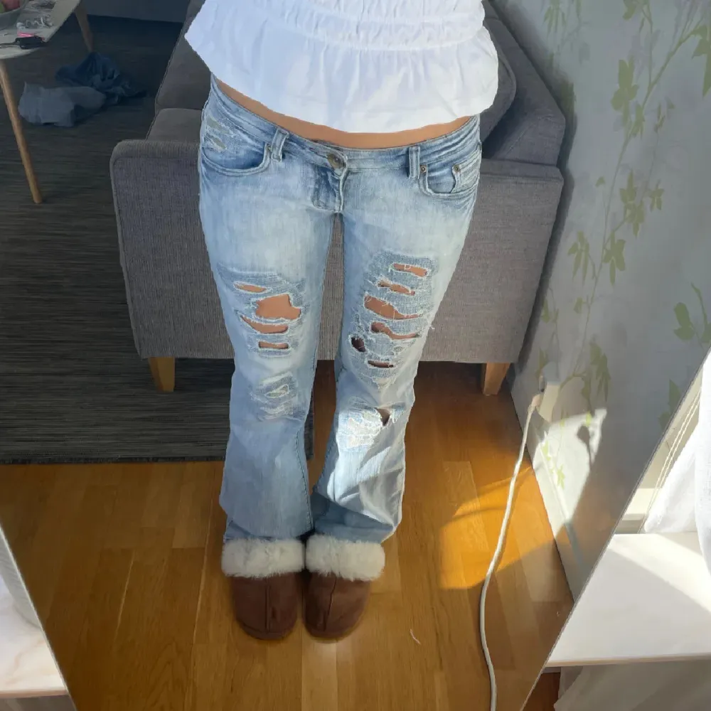 Säljer ett par ljusa jeans med slitningar på framsidan. De har en normal passform och är lågmidjade. Perfekta för en avslappnad stil.. Farkut & Housut.