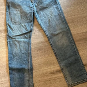 Blå jeansbyxor - Säljer ett par klassiska blå jeansbyxor med normal passform. De har en traditionell femficksdesign och en snygg tvättad look. Perfekta för en avslappnad stil.