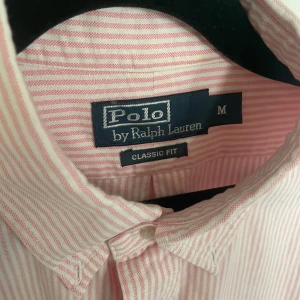 Randig Ralph Lauren skjorta - Riktigt snygg Ralph Lauren skjorta som passar perfekt till sommaren. ☀️ ☀️   Färgen syns bäst på första bilden pga ljuset 🚀🚀  Skicket är mycket bra, inte använd många gånger alls. 🌟🌟 Storlek M men sitter mer som L skulle jag tro. Mått: Längd - 78cm Bredd, armhåla - 55cm  Skriv om det är något du undrar över!🤩🤩