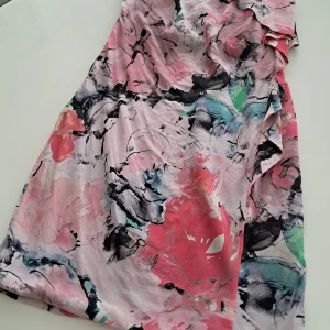 Mönstrad klänning från Pinko I Siden - Säljer en vacker klänning från Pinko i ett färgglatt mönster med rosa, svart och gröna toner. Klänningen har volangdetaljer och är tillverkad i 100% siden vilket ger en lyxig känsla. Perfekt för sommarens festligheter!