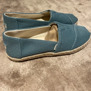 Turkosa skor från TOMS - Somrig turkosa skor från TOMS med en avslappnad stil. De är i modellen Alpargata Rope och är aldrig använda, alltså i nyskick. Storlek 6 men invändig sula möter 23 cm. 