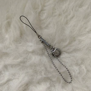 Silverfärgad nyckelring med äppelhänge - Snygg silverfärgad nyckelring med ett glittrigt äppelhänge. Perfekt som accessoar för att ge din väska eller nycklar lite extra bling. Kedjan är av kulmodell och hänget har små gnistrande stenar.