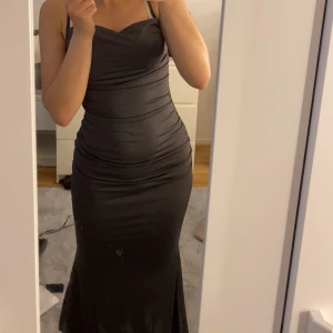 Mörkgrå långklänning - Elegant svart långklänning med smala axelband och draperad design. Perfekt för en festlig kväll med sin figurnära passform och stilrena look. Använd 2 gånger. DU STÅR FÖR FRAKT