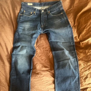 Blå jeans Levi's 501 - Snygga blå jeansbyxor från Levi's med klassisk femficksdesign och knappgylf. Perfekta för en avslappnad stil. De har en rak passform, W30 L30. Tvätten är riktigt snygg. Mycket bra skick. Kom med bud!😛