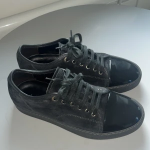 Svarta sneakers från Lanvin - Snygga mörkblå sneakers från Lanvin med en kombination av mocka och glansigt material på tån. Skorna har snörning och en stilren design som passar perfekt för en trendig look. Inget kvitto eller box finns ej med i köpet. Priset kan diskuteras 👌