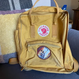 Gul ryggsäck från Fjällräven - Säljer en klassisk gul Fjällräven Kånken ryggsäck. Välanvänd men har fortfarande mycket liv kvar att ge! Ryggsäcken har justerbara axelremmar och ett bärhandtag upptill. Perfekt för både vardag och äventyr!