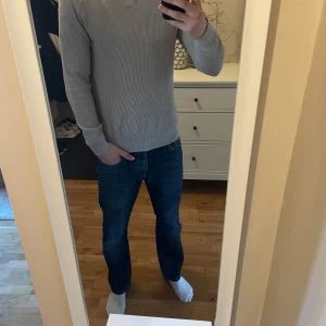 Beige ribbad tröja från Dressmann - Säljer en stilren beige ribbad tröja från Dressmann. Tröjan har en klassisk krage och långa ärmar, perfekt för en avslappnad men ändå snygg look. Storlek M