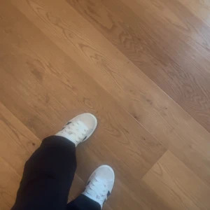 Vita sneakers från Adidas - Snygga vita sneakers från Adidas med klassiska svarta ränder på sidan. Perfekta för en avslappnad stil och passar till det mesta i garderoben. Storlek 38