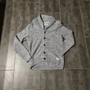 Grå stickad kofta från Pier One - Säljer en snygg grå stickad kofta från Pier One. Koftan har en mysig krage och knappar framtill. Perfekt för kyliga dagar eller på en skön morgon där solen skiner och det är lite kyligt. och ger en stilren look. Passar bra till både jeans och chinos.