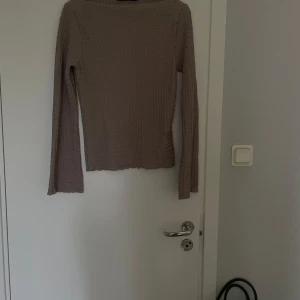 Beige ribbad långärmad topp  - Säljer en beige långärmad topp  i storlek XS. Tröjan är ribbad med en smal passform och har en mjuk, stretchig känsla. Perfekt att styla med jeans eller kjol för en enkel och snygg look.