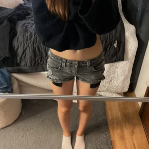 Grå slitna jeansshorts - Säljer ett par grå jeansshorts med slitningar. Shortsen har fem fickor, bälteshällor och låg midja. Perfekta för sommaren och ger en cool, avslappnad look. midjemått- 36 cm