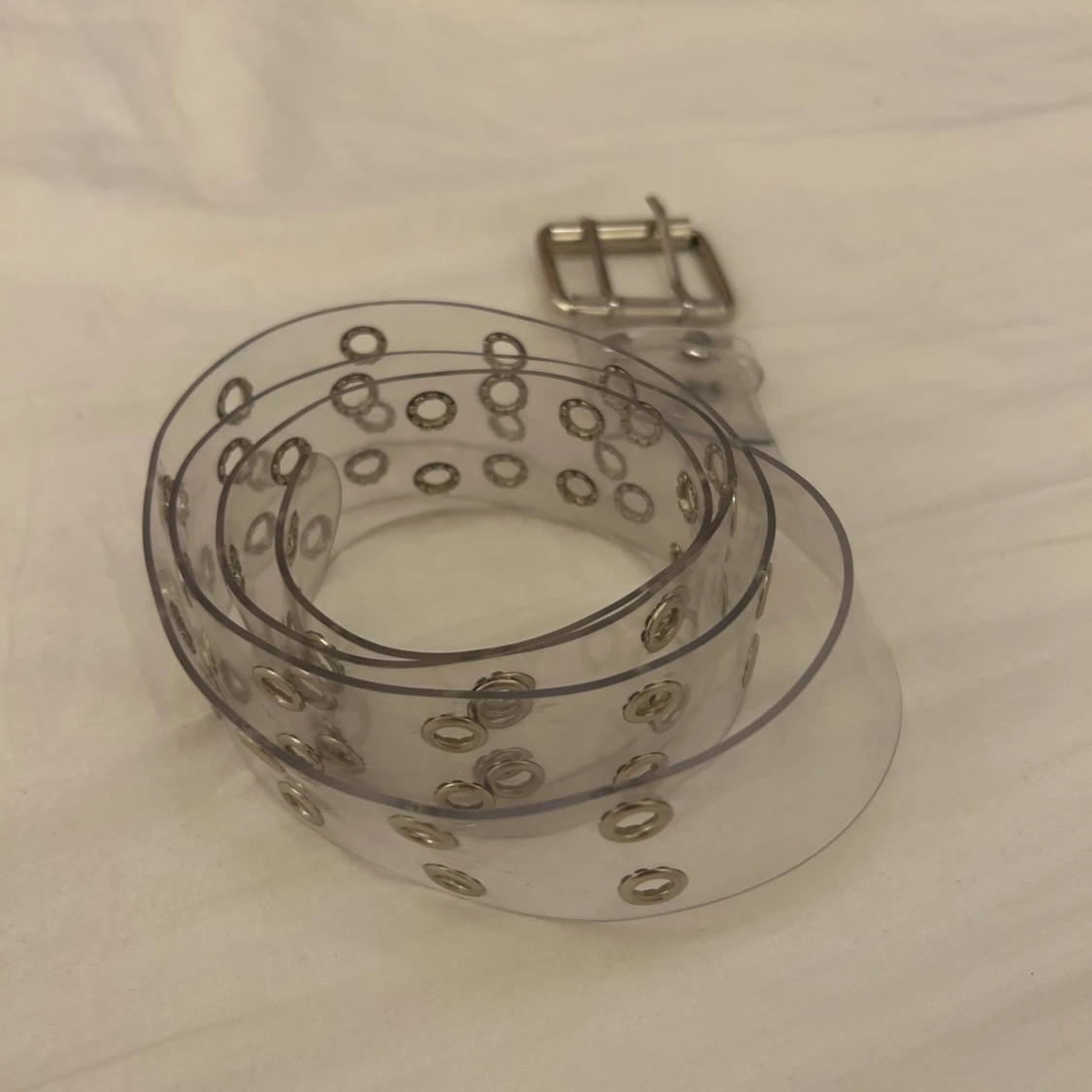 Transparent bälte med silverfärgade nitar