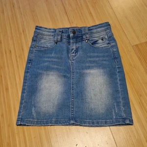 Blå jeanskjol från Creamie - Säljer en klassisk blå jeanskjol från Creamie, kjolen har en rak tajt passform och är i ett mjukt denimtyg med lätt slitna detaljer framtill och baktill. Perfekt att matcha med en enkel topp eller hoodie. Passar xxs till xs.