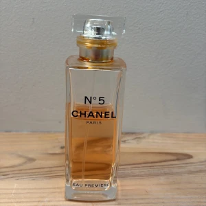 Chanel No. 5 Eau Première Parfym - Elegant parfym från Chanel i modellen No. 5 Eau Première. Flaskan är rektangulär i genomskinligt glas med guldiga detaljer och en klar fyrkantig kork. Doften är klassisk och tidlös, perfekt för dig som gillar lyxiga och ikoniska parfymer. Mer än hälften kvar, ca 50 ml återstår.