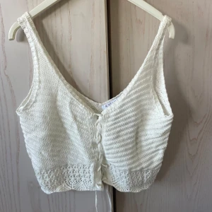 Vit stickad linnetopp från Amisu - Säljer en vit stickad linnetopp från Amisu med v-ringning och knytning framtill. Toppen har fina virkade detaljer nertill och är kroppad. Storlek S. Aldrig använd.