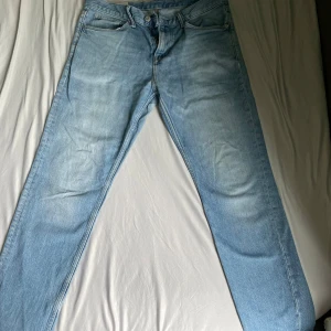 Ljusblå slim fit jeans från H&M - Säljer ett par ljusblå slim fit jeans från H&M. Klassisk femficksmodell med dragkedjegylf och raka ben. Jeansen är tillverkade i bomull med lite elastan för extra stretch och komfort.