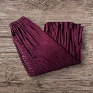 Plisserade vinröda/lila byxor  - Säljer en vinröda plisserade byxor med resår i midjan. Byxorna har ett elegant fall och är perfekt för dig som gillar en stilren look med lite extra volym. Passar snyggt till både sneakers och boots. Hittar ej storlek men passar L/XL för en luftig look. 