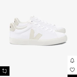 Vita sneakers från Veja med beige detaljer - Säljer ett par fräscha vita sneakers från Veja med beige V-logga på sidan och beige detalj vid hälen. Skorna har snörning och platt sula, perfekt för en clean och stilren look. Passar till det mesta och är riktigt bekväma. Säljer för ja råkade beställa för stor storlek för mig. Använda endast 2 gånger.