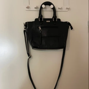 en svart medium-liten väska  - en svart medium-liten väska med leopard print på insidan. aldrig använt själv men har köppt den från loppis. mycket bra skick!