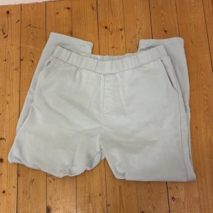 Ljusgrå mjukisbyxor från Kosta Williams - Ljusgrå mjukisbyxor från Kista Williams x ABOUT YOU med elastisk midja och sidofickor. Byxorna har en avslappnad passform och är perfekta för en chill stil. Materialet är mjukt och bekvämt, perfekt för vardagsbruk. Storlek Xl men sitter som L.