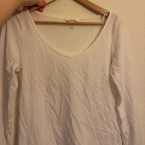 Vit långärmad topp med v-ringning - Säljer en enkel och stilren vit långärmad topp med djup v-ringning. Perfekt basplagg som passar till det mesta. Mjuk och skön bomullskänsla. Snygg att styla med jeans eller kjol.