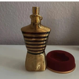Jean Paul Gaultier Le Male Elixir 125ml - Säljer en lyxig parfymflaska från Jean Paul Gaultier, Le Male Elixir Parfum. Flaskan är formad som en manlig torso i guld med svarta ränder och har en elegant, glänsande finish. Kommer med en vinröd och guldig förvaringsask. Rymmer 125 ml men det är parfym till det andra sträcket nerifrån så cirka 50 ml 