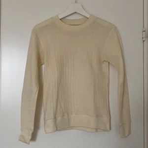 Gräddvit ribbad stickad tröja - Mjuk beige stickad tröja med ribbat mönster och rund hals. Tröjan har långa ärmar och breda muddar vid ärmslut och nederkant. Skriv för fler bilder. Finns i Östersund, annars står köparen för frakten! 