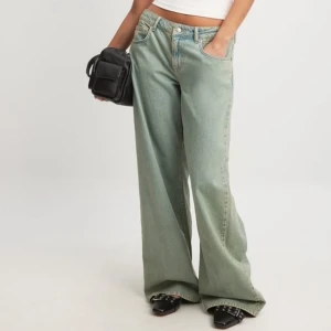 Grönblå wide jeans med låg midja - Snygga gröna jeans med breda ben och låg midja. Jeansen har klassisk femficksdesign och stängs med knapp och dragkedja. Perfekta för en avslappnad och trendig look. 34 men passar mig som är en 36