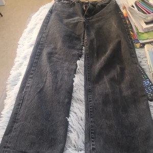 Svarta wide jeans från 157 - Säljer ett par svarta jeans från 157 med breda ben och råa kanter nertill. Jeansen har klassisk femficksdesign, dragkedja och knapp framtill. Perfekta för dig som gillar en avslappnad och trendig look.