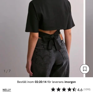 Svart croppad topp med knyt från Nelly - Svart croppad topp från Nelly med korta ärmar och snygg knytning i ryggen. Toppen har en rak passform framtill och öppen rygg som ger en cool och trendig look. Perfekt att styla med höga jeans för en modern vibe. S