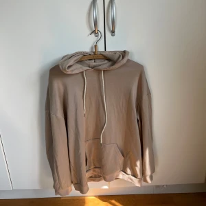 Beige hoodie med blå fjärilstryck - Säljer en oversized beige hoodie med stor huva och dragsnören. På ryggen finns ett stort tryck med en blå fjäril på ryggen .  Storlek L/XL