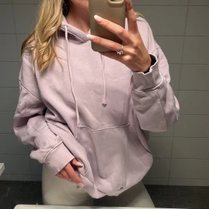 Ljuslila hoodie från Weekday - Supermjuk hoodie från Weekday i en ljuslila nyans. Oversized fit med stor känguruficka, huva och snörning. Perfekt för chill dagar och enkel att styla med jeans eller leggings. Tillverkad i bomullsmix för extra comfort. 