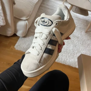 Adidas Campus sneakers i beige mocka - Snygga Adidas Campus sneakers i beige mocka med klassiska svarta ränder på sidorna och vit sula. Köpta för cirka ett år sedan och är sparsamt använda! Storlek 36 2/3. Finns såklart tecken på användning men är inte slitna 💕