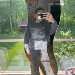 Grå sweatshirt med tryck från H&M Divided - Grå sweatshirt från H&M Divided med stort vitt tryck framtill med texten 'ALWAYS BY YOUR SIDE' och motiv av en skidlift. Tröjan har rund hals, ribbade muddar och en avslappnad passform. Perfekt för chill dagar eller när du vill ha en cool streetstyle.