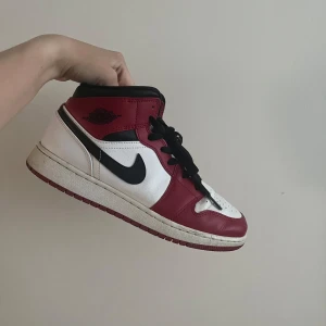 Nike Air Jordan 1 Chicago sneakers - Nike Air Jordan 1 Chicago i klassisk röd, vit och svart färg. Skorna har svart swoosh, svarta skosnören och hög siluett. Tillverkade i skinn med perforerad tåbox och ikonisk Air Jordan-logga på sidan. Perfekta för dig som gillar streetstyle och sneakerskultur.