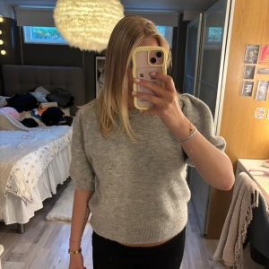 Grå stickad tröja från Gina Tricot - Säljer en mysig ljusgrå kortärmad stickad tröja från Gina Tricot. Tröjan är endast använd ett fåtal gånger och i mycket bra skick🤍